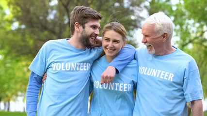 Group of happy volunteers hugging and smiling at park, teamwork cooperation