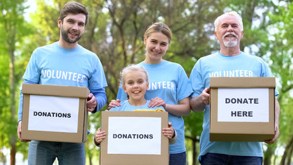 Smiling volunteers holding donation boxes looking camera, charity project, help