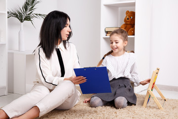 Child with therapist working on pronunciation and sounds together sitting in the class