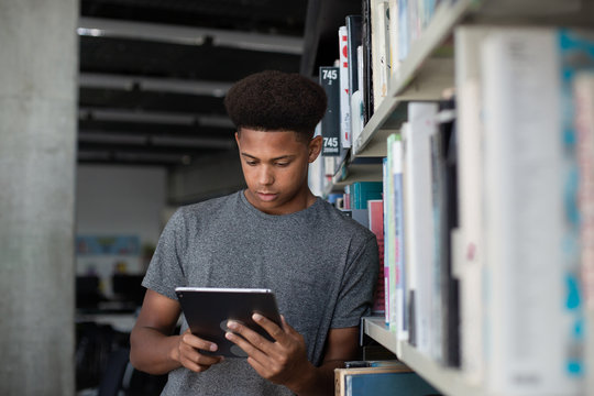 High School African American Male Student Studying With Digital Tablet In Library