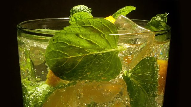 Glass of Cocktail with lemon, mint, ice moving on a turntable
