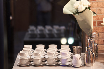 many white ceramic mugs with a metal teapot. Tea party at the celebration.