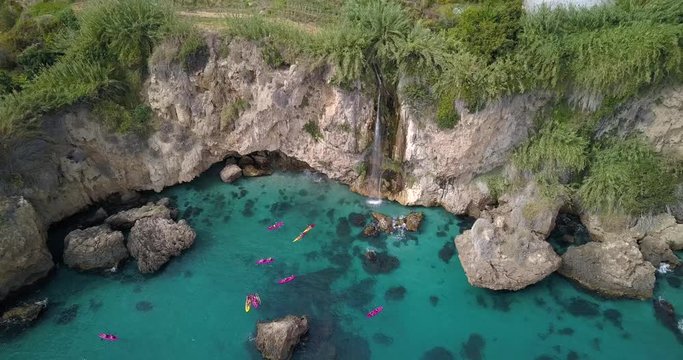 Aerial of the Cascada de Maro waterfall in the Acantilados de Maro-Cerro Gordo park near Nerja, Andalusia, Spain. This waterfall can only be visited by sea. Zoom out and up overhead drone footage