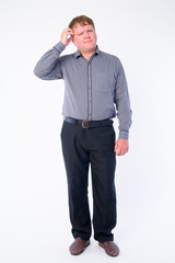 Full body shot of confused overweight businessman scratching head