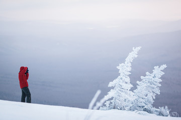 Hiker in the winter forest traveling in the mountains