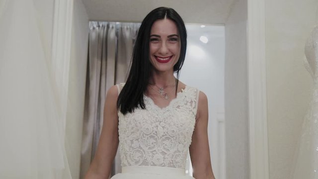Beautiful girl measures a wedding dress in a bridal salon.