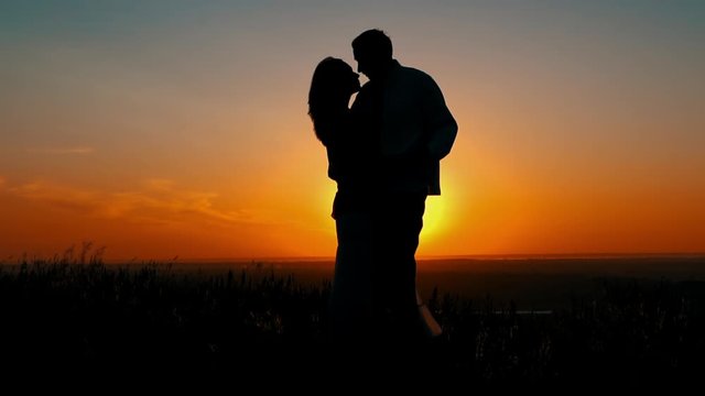 silhouette of a couple in love kiss at sunrise romantic honeymoon warm nature landscape