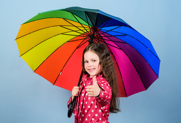 Rainy weather with proper garments. Rainy day fun. Happy walk under umbrella. Enjoy rain concept. Fall season. Kid girl happy hold colorful rainbow umbrella. There is rainbow always after the rain