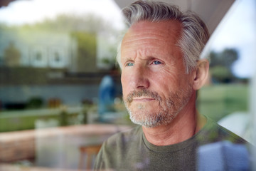  Senior Man Standing And Looking Out Of Kitchen Door Viewed Through Window