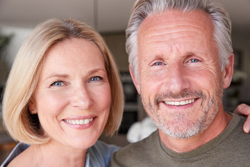 Portrait Of Smiling Senior Couple Standing At Home In Kitchen Together
