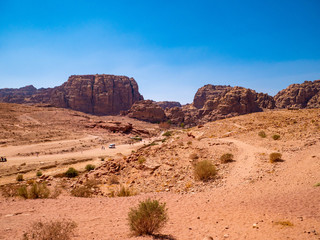 View of the valley of the historic site of Petra, Jordan, orange desert full of temples and a roman amphitheatre, seen from aerial perspective from a sandstone mountain
