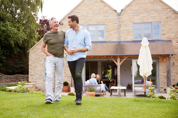 Senior Father And Adult Son Walking And Talking In Garden Together