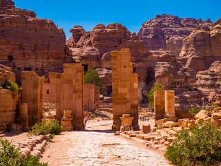 Cobblestone street leading through large sandstone columns of a historic monument, ruin in the...