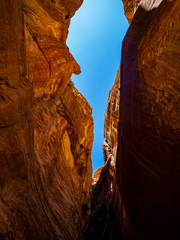 Orange walls of a canyon in the historic sight of Petra, Jordan, in the mountains of the desert under blue sky