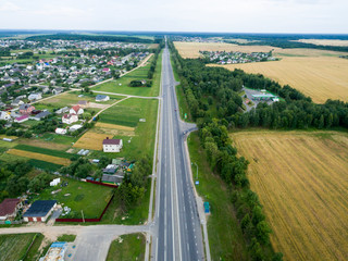 Fototapeta na wymiar Top view asphalt road, highway, a crossroads in the village on a bright sunny day. Aerial photo with green forest, grass