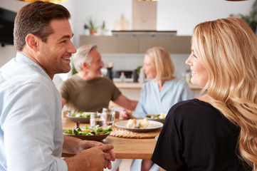 Family With Senior Parents And Adult Offspring Eating Meal Around Table At Home Together