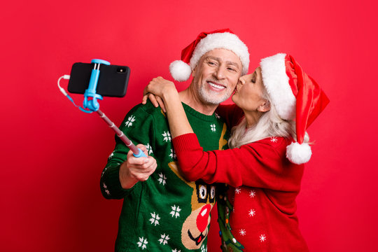 Blogging time social media concept. Photo of two romantic dreamy grey white haired sweethearts people married spouses making picture on cell using monopod hugging kissing in cheek isolated background