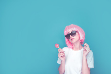 Young woman in a pink wig and dark glasses isolated in a studio