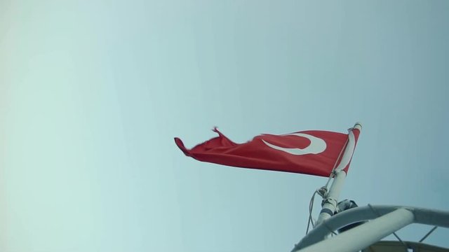 Turkish Flag Blowing On Wind.Red Turkish Symbol Flag On Wind.Turkish Flag On Side Of Boat.Banner On Boat Ship In The Wind in Istanbul at Sunset.Vivid Red Turkish Flag Flutter On Ster.