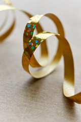 Golden curly ribbon on brown kraft paper background. Serpentine with curls for use as a christmas, anniversary, marriage, wedding or celebration background. Vertical with copy space.