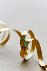 Golden curly ribbon on brown kraft paper background. Serpentine with curls for use as a christmas, anniversary, marriage, wedding or celebration background. Vertical with copy space.