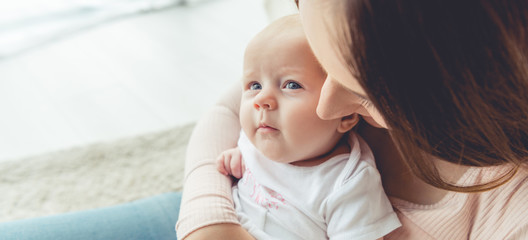panoramic shot of mother holding her child in apartment