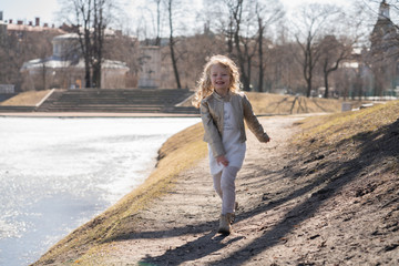 pretty cute caucasian blonde little kid girl walking in the cold spring city park alone and happy 