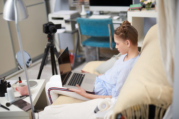 Charming teenage girl using modern laptop at home