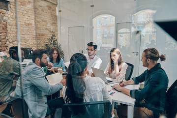 Group of young modern people in smart casual wear using discussing business while working in the board room
