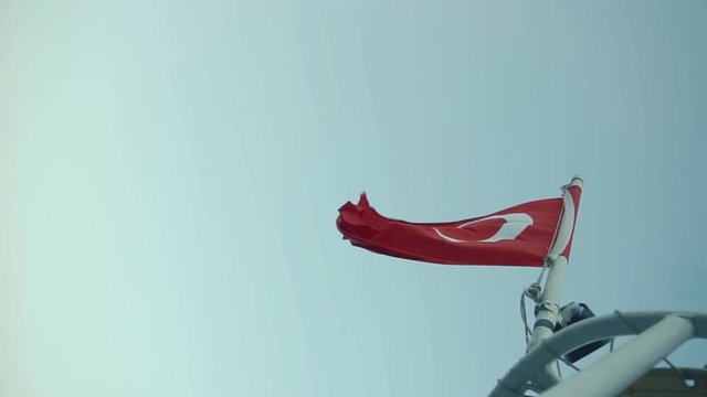Turkish Flag Blowing On Wind.Red Turkish Symbol Flag On Wind.Turkish Flag On Side Of Boat.Banner On Boat Ship In The Wind in Istanbul at Sunset.Vivid Red Turkish Flag Flutter On Ster.