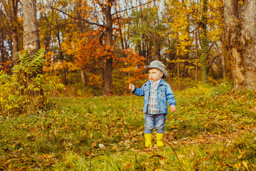 Boy in a cowboy hat walks in a forest in autumn