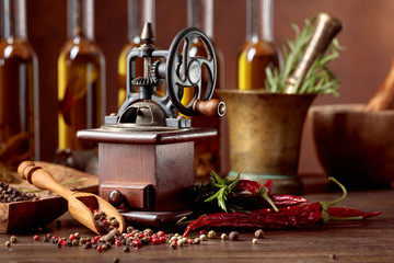 Old pepper mill with cooking utensils, bottles of olive oil, spices and rosemary on a wooden table. © Igor Normann
