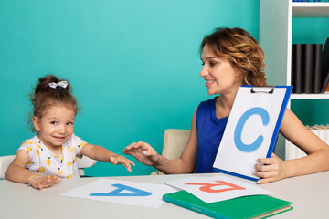 Woman with kid girl training speech together sitting in the white room