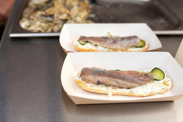 The counter on which lies a fish sandwich in an eco-friendly paper plate. Food and cooking equipment at a street food festival