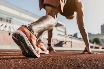 Fotobehang Gymnastiek Close up of male athlete getting ready to start running on track . Focus on sneakers  © InsideCreativeHouse