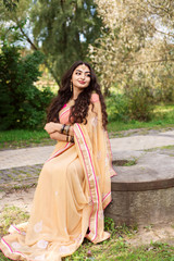 Obraz na płótnie Canvas Indian girl in saree sitting in park