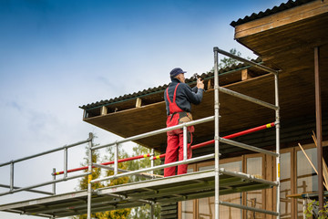 man standing on scaffolding and restore old wooden house roof structure