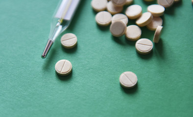 mercury thermometer and tablets on a green background