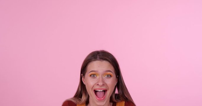 Excited teenage girl on light pink background