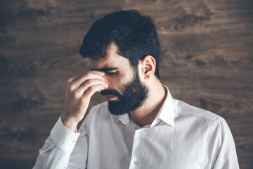 man hand in nose on brown wall background