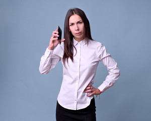 natural caucasian girl speaks angry with her mobile phone in front of a blue background