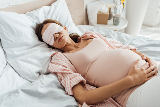 pregnant woman lying in bed in sleep mask