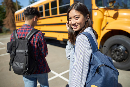 Smiling Asian girl is going to school bus