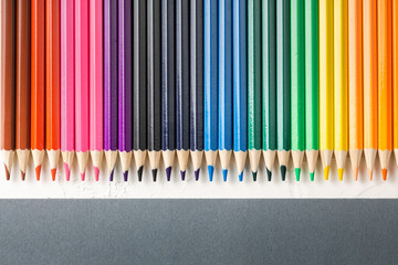 colored pencils in row on a gray background top view.