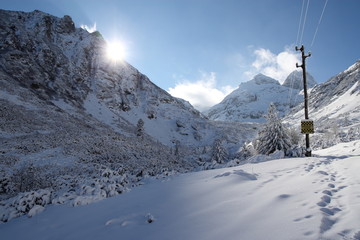 Fototapeta na wymiar Power lines running through a snow covered mountain landscape