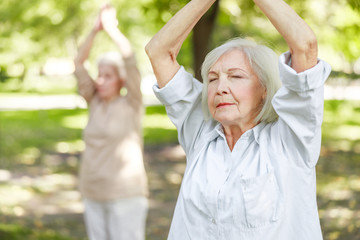 Serene old woman doing qigong exercise in the park