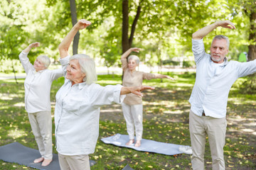 Naklejka na ściany i meble Joyful old people practicing chi kung in the park