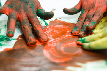 red hands in paints on background of light table painted in different colors