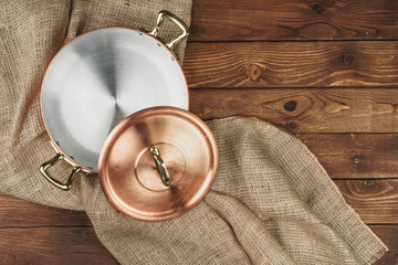 Copper pot on the dark wooden table, top view