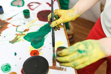 yellow hands in paints on light table painted in different colors